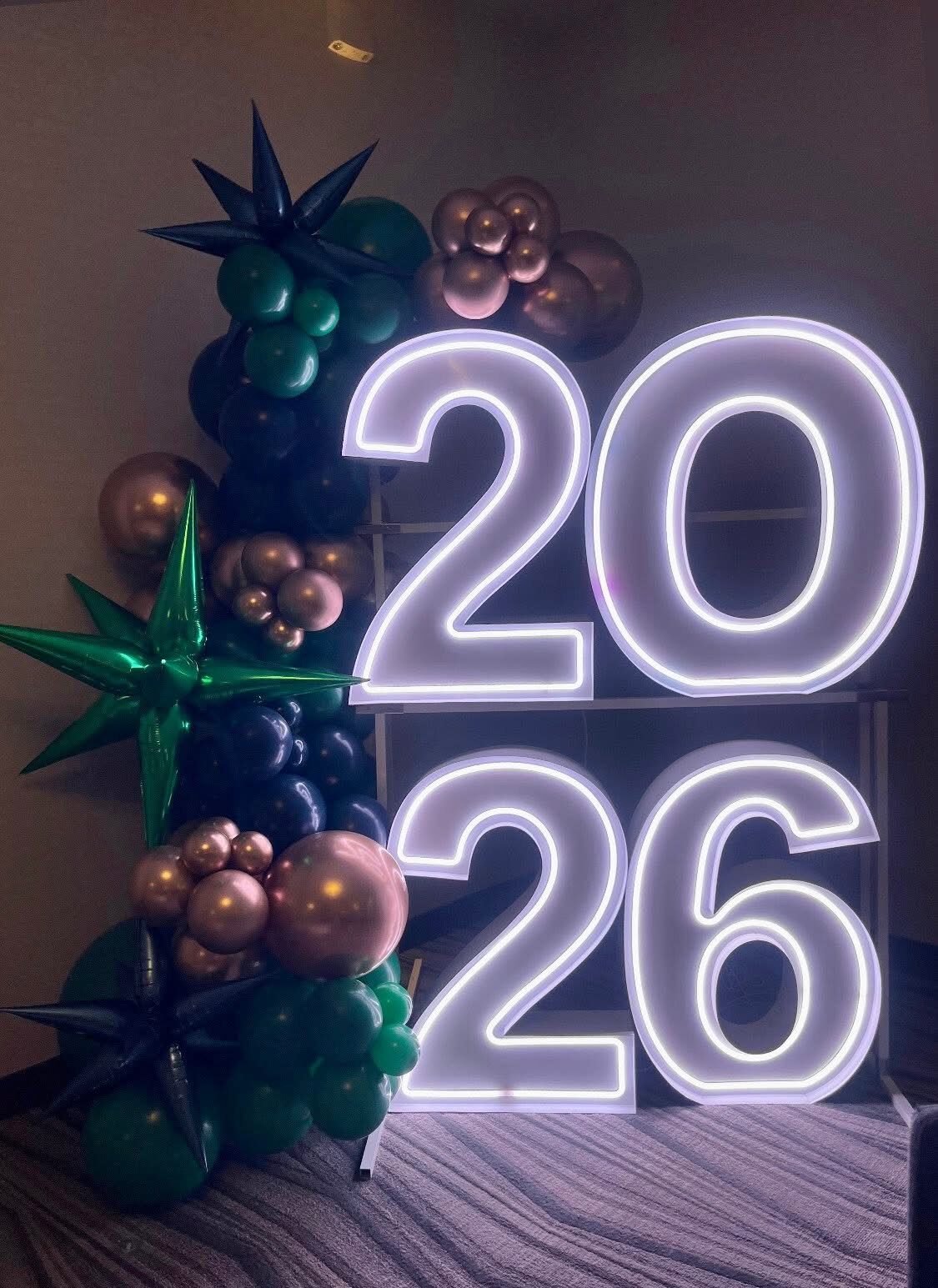 2026 in white Illuminate numbers beside a green and rose gold balloon cluster