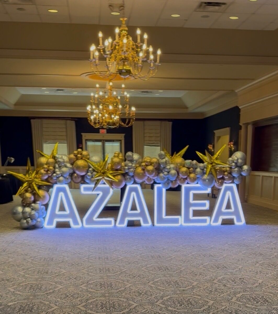 AZALEA in blue and purple Illuminate letters under a ballroom chandelier