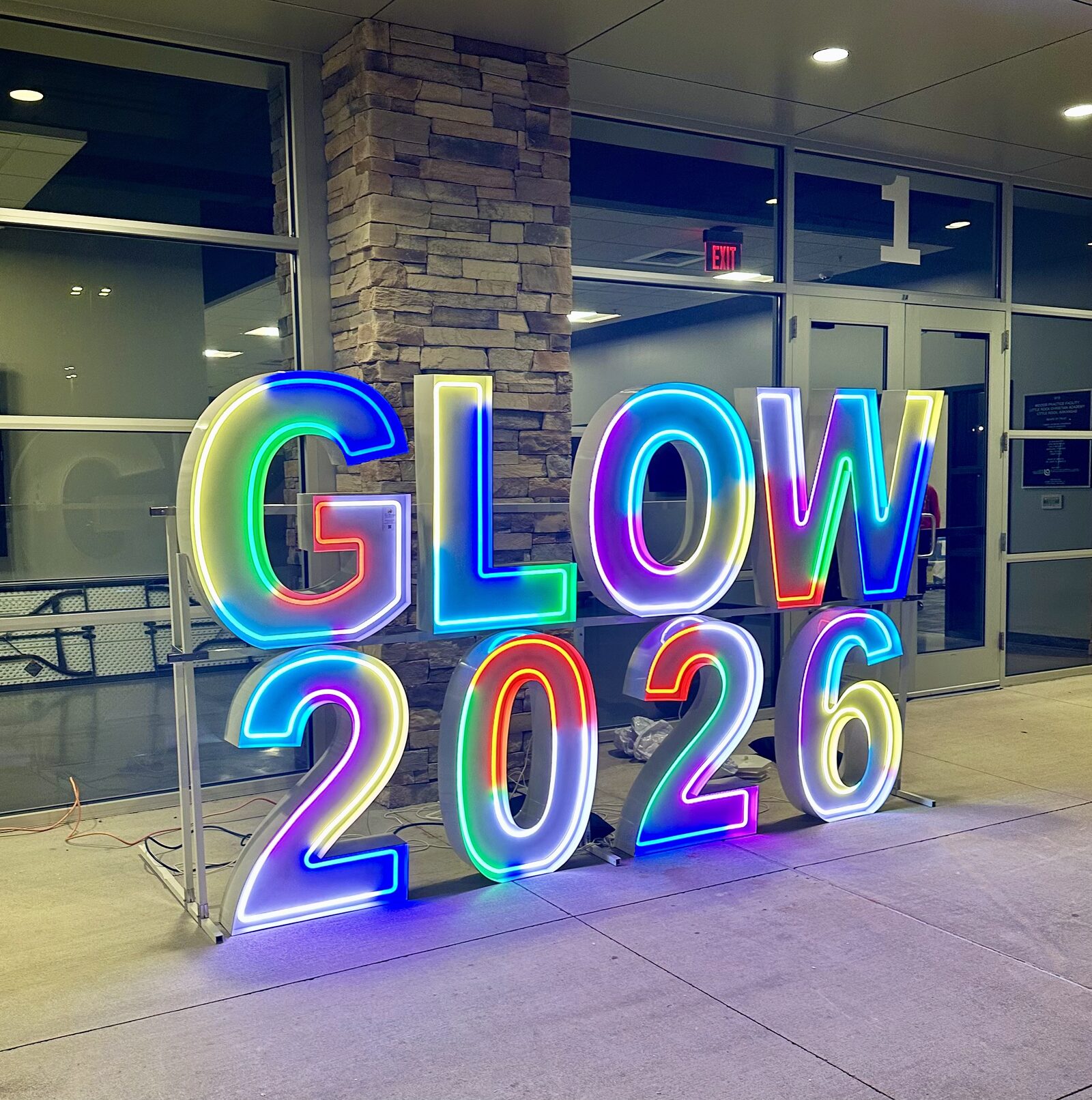 GLOW 2026 in color-changing Illuminate letters outside a school entrance