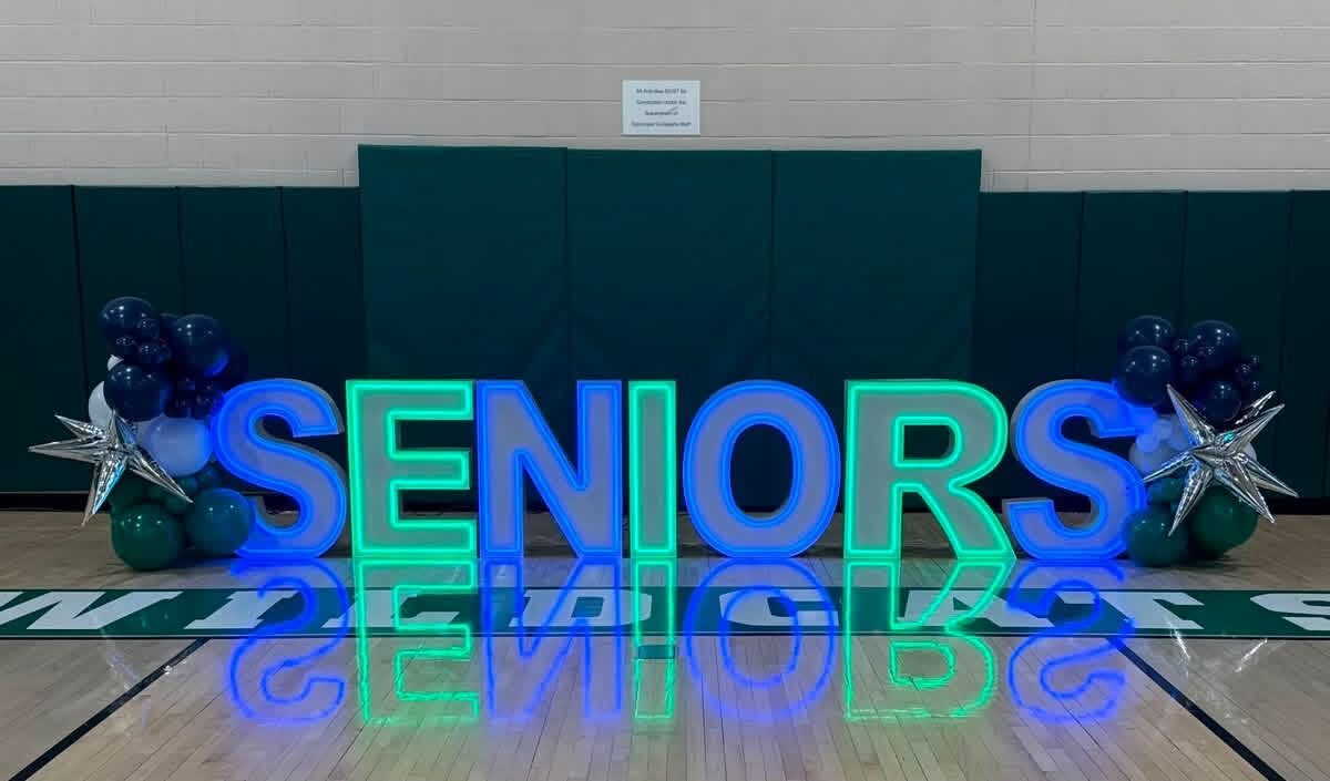 SENIORS in blue and green Illuminate letters on a gym floor